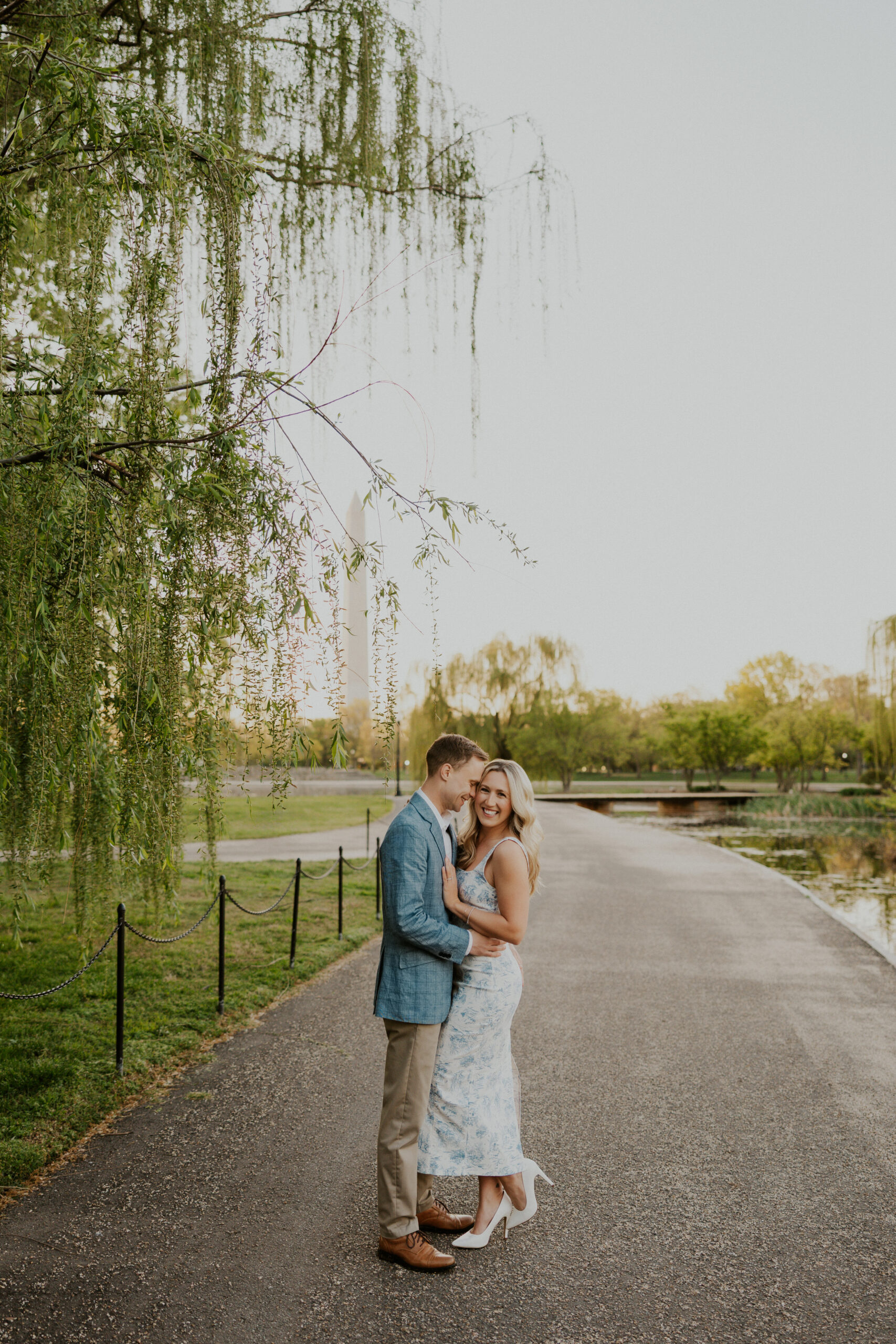 Engaged couple laughing in front of the Washington Monument during sunrise photos at Constitution Gardens