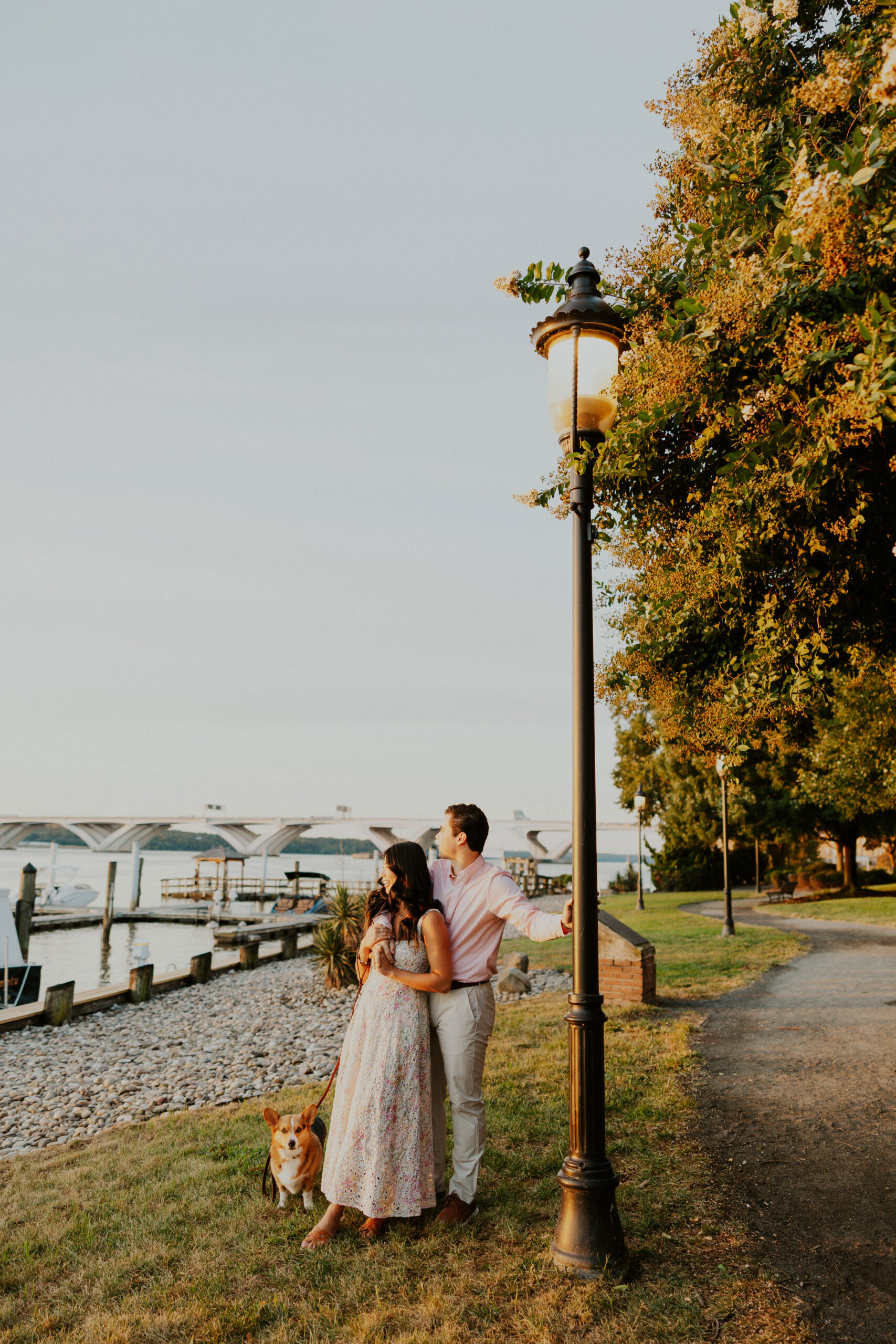 Couple standing together on the Alexandria VA waterfront at sunrise during romantic engagement session.