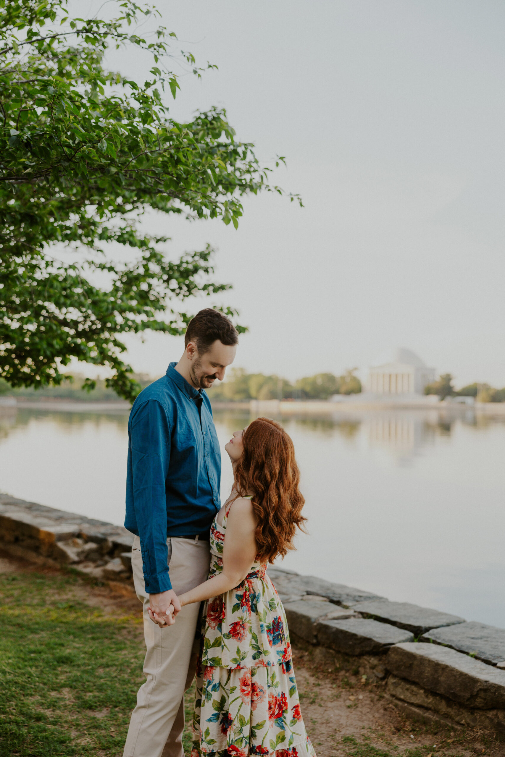 Couple during sunrise engagement session at the Tidal Basin in Washington DC with Jefferson Memorial in backgroundCouple during sunrise engagement session at the Tidal Basin in Washington DC with Jefferson Memorial in background